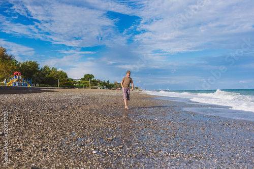 White barefoot kid enjoying warm sea water at sunny scenic summer beach during trip in Turkey. 