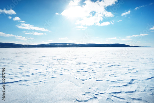 Panoramic view of the frozen lake. Snow-covered mountains and coniferous forest in the background. Clear blue sky. Kola Peninsula, Murmansk region, Polar Circle, Karelia, Russia photo