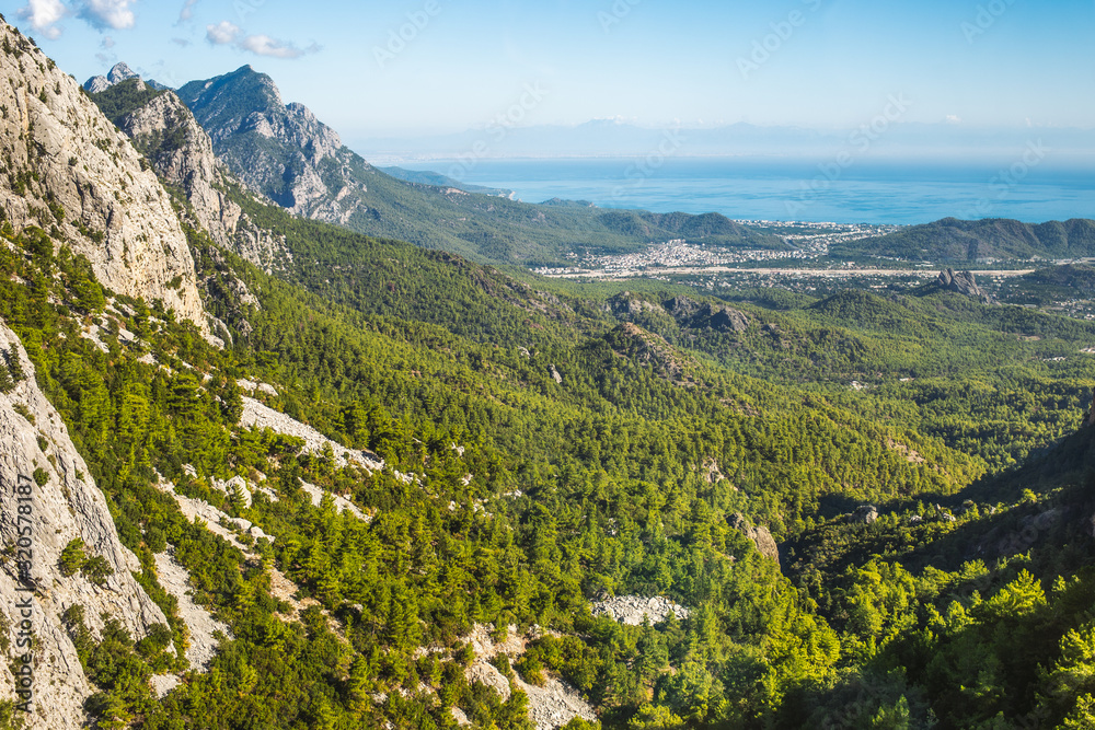 Beautiful sunny amazing view at high mountains with lush green growth of trees at hills as seen from mountain. Idyllic natural peaceful photo background. Turkey. Beautiful sunny amazing view at high mountains with lush green growth of trees at hills as seen from mountain. Idyllic natural peaceful photo background. Turkey.