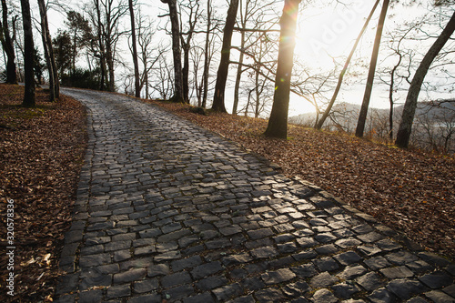 Cobblestone road going down. Sunset in forest. Road of large stones. Spring time.