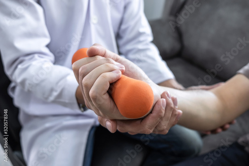 Doctor physiotherapist treating arm pain patient doing physical therapy exercises with his therapist in clinic - sport physical therapy concept