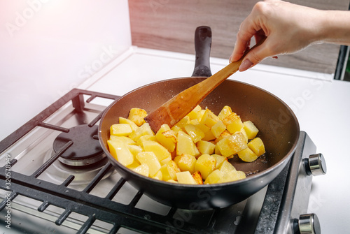 Vászonkép A woman frying potatoes in the kitchen. Fried potato wedges