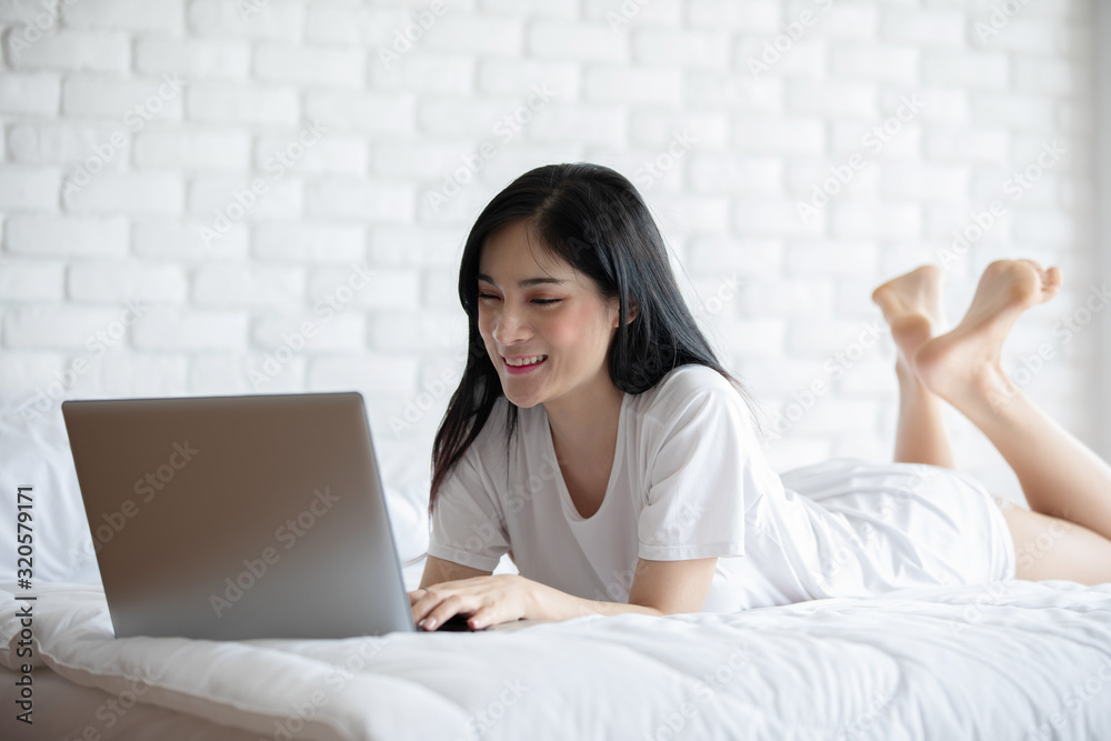 Beautiful Attractive Asian young woman lying on bed and using computer laptop for using social media and shopping online relax in cozy bedroom in holiday,Lifestyle in bedroom Concept Beautiful Attractive Asian young woman lying on bed and using computer laptop for using social media and shopping online relax in cozy bedroom in holiday,Lifestyle in bedroom Concept