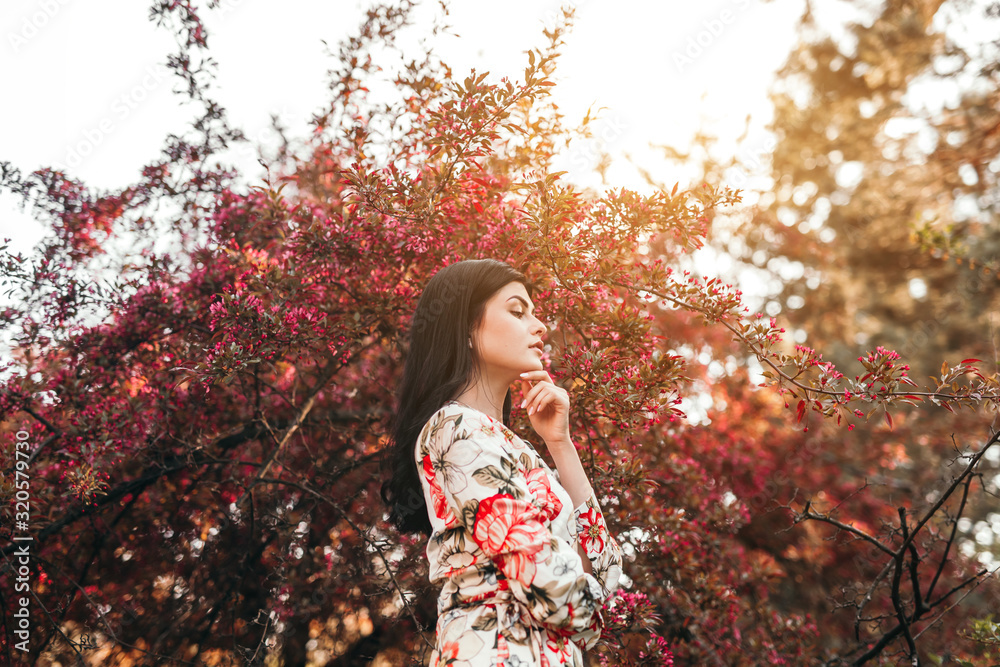 Elegant woman near blooming bush in garden