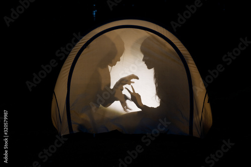 Schilderij op canvas Children making shadow puppets in a camping tent at night