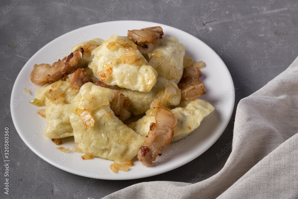 Pierogi, dumplings served with caramelized salted onion in bowl. Traditional Polish dish - pierogi or dumplings with meat, potatoes, mushrooms, sour cream and fried onions. Close up, space for text Pierogi, dumplings served with caramelized salted onion in bowl. Traditional Polish dish - pierogi or dumplings with meat, potatoes, mushrooms, sour cream and fried onions. Close up, space for text