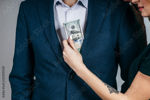 A girl takes money out of a jacket pocket of a male businessman