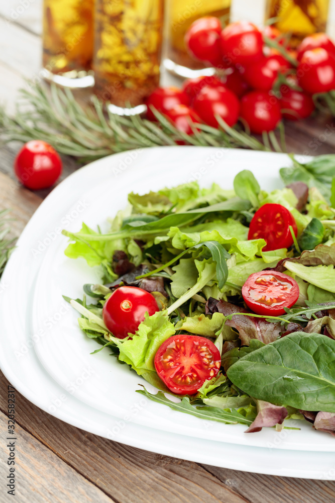 Fresh mixed salad with cherry tomatoes on white plate.