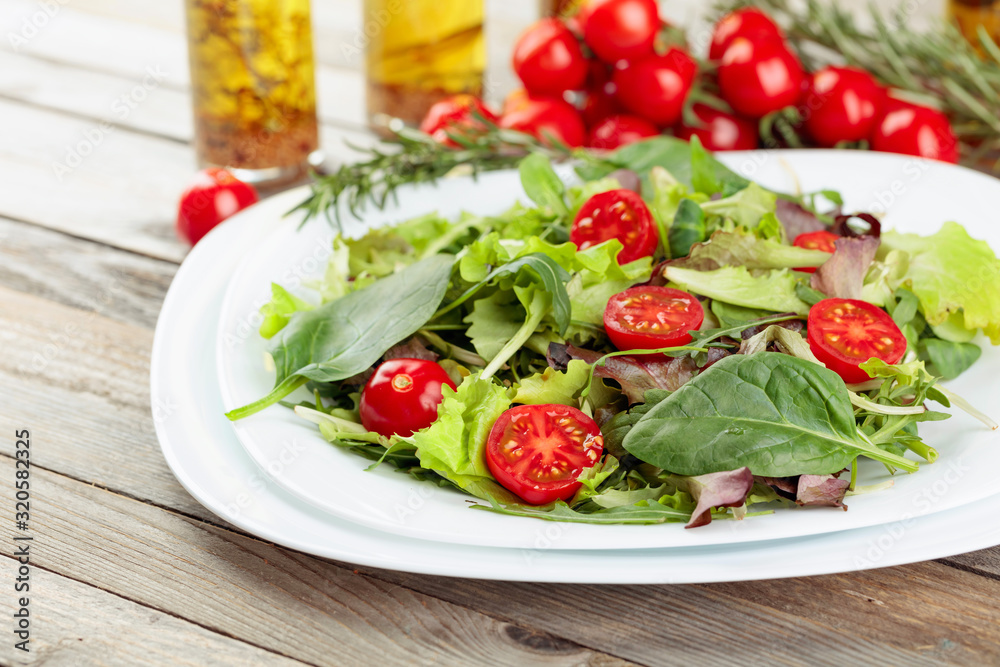 Fresh mixed salad with cherry tomatoes on white plate. Fresh mixed salad with cherry tomatoes on white plate.