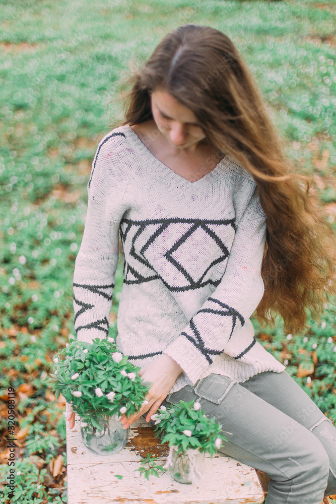 pretty girl holding white spring flowers walking through the green forest pretty girl holding white spring flowers walking through the green forest