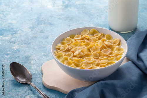 Breakfast with cereal. Flakes with milk. A plate of cereal with milk on a blue table. Perfect for breakfast. Free space for text.