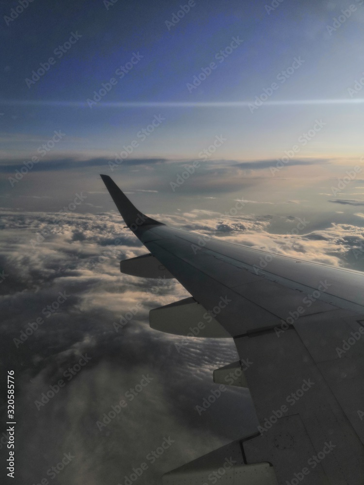 wing of an airplane flying above the clouds wing of an airplane flying above the clouds