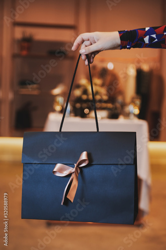 Girl holds beautiful dark blue gift bag with a pink bow. Special evening with presents. Valentine's Day or Women's Day.