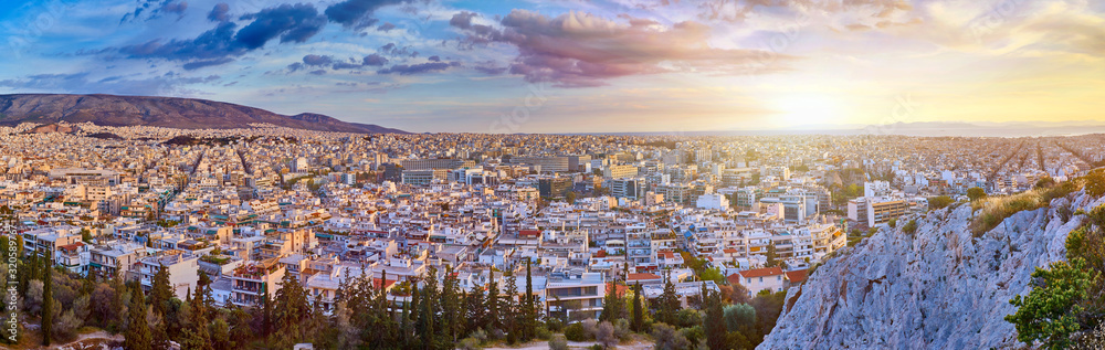 Obraz premium An evening cityscape of many buildings of Athens City, Greece. View from Filopappou Hill or Hill of the Muses. Colorful spring landscape. Urban skyscraper skyline rooftop view at night.