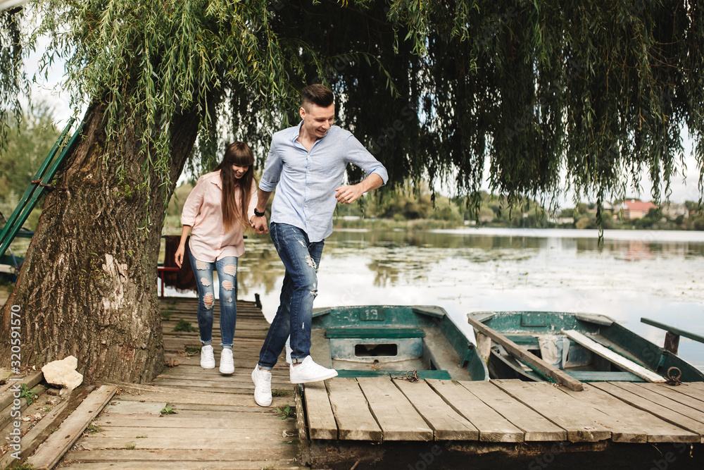 Happy young couple outdoors. young love couple running along a wooden bridge holding hands.