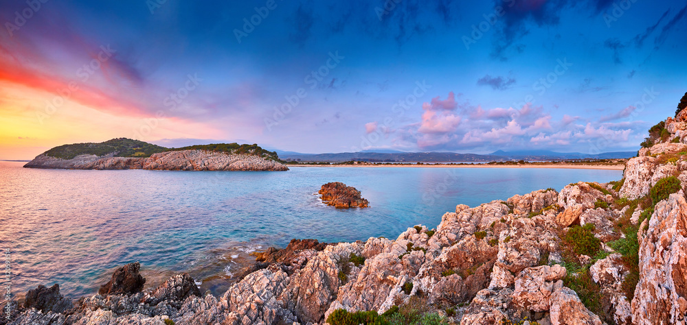 Amazing sunset view with multicolored clouds. Incredibly romantic sunrise on Voidokilia beach, Ionian Sea, Pilos town location, Greece, Europe. View of the ocean through the rocky shore