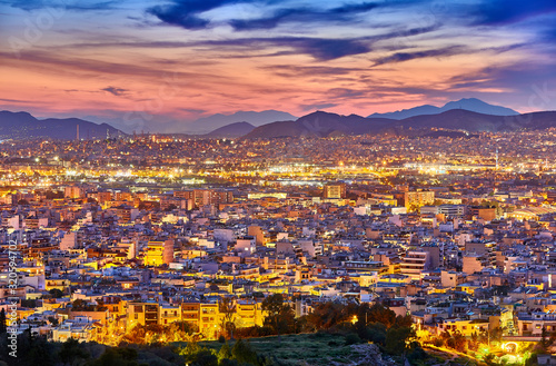 An evening cityscape of many buildings of Athens City, Greece. View from Filopappou Hill or Hill of the Muses. Colorful spring landscape. Urban skyscraper skyline rooftop view at night. © zicksvift
