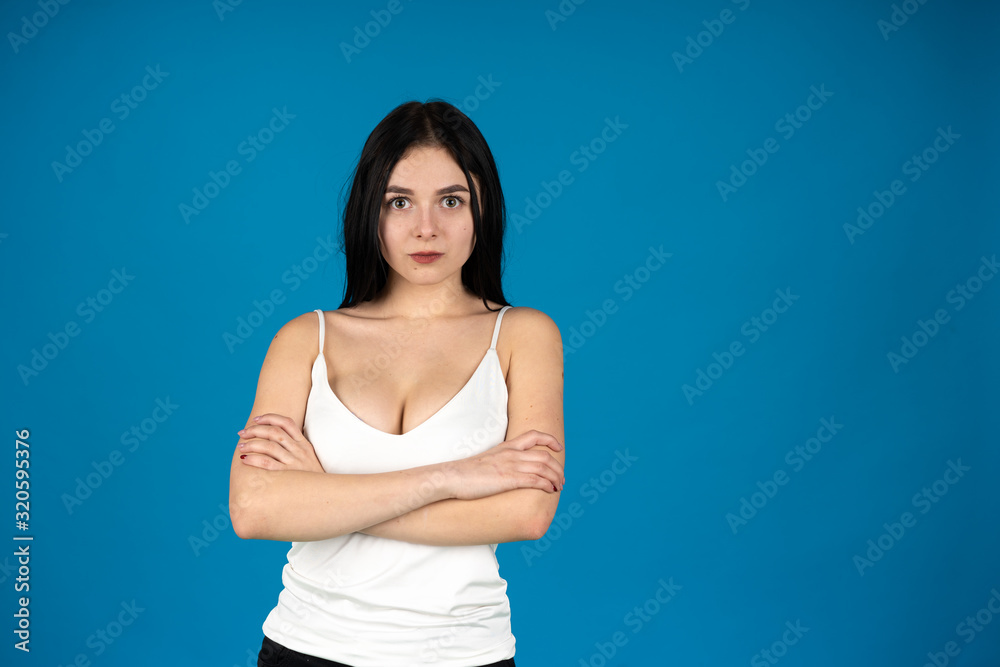 Front view of brunette girl posing with crossed arms isolated on blue background Front view of brunette girl posing with crossed arms isolated on blue background
