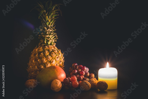 Still life of fruit in the dark lit by candles