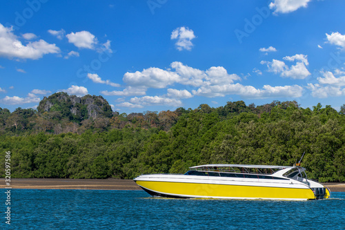 The yellow speed boat at sea with blue sky and mountain background © Ratchapon