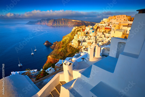 Fira town on Santorini island, Greece. Traditional houses churches with blue domes over the Caldera, Aegean sea. Oia village in the morning light. Amazing sunrise view with white houses in Oia village