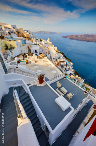 Fira town on Santorini island, Greece. Traditional and famous houses and churches with blue domes over the Caldera, Aegean sea. Terraces of Santorini hotels in the morning light.