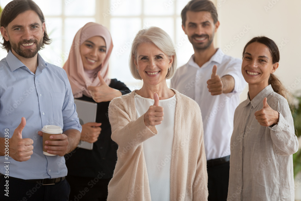 Happy multiethnic colleagues show thumbs up gather in office Happy multiethnic colleagues show thumbs up gather in office