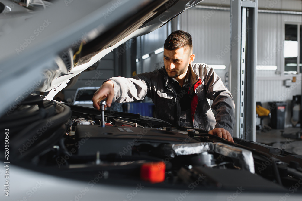 Mechanic working and holding wrench of service order for maintaining car at the repair shop Mechanic working and holding wrench of service order for maintaining car at the repair shop