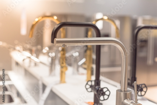Selective focus of shiny faucets with pull out sprout and price tag at furniture showroom in Texas, USA