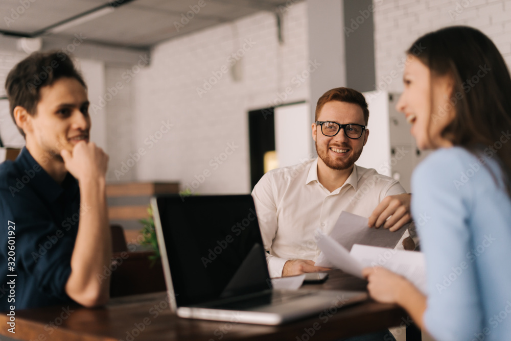 The three business people working at the table in the office. Concept of teamwork young business people. Concept of office life. The three business people working at the table in the office. Concept of teamwork young business people. Concept of office life.