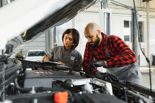 Male and female mechanics working on car