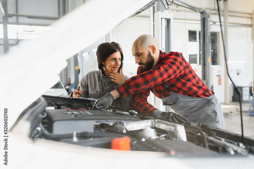 auto service, repair, maintenance and people concept - mechanic men with wrench repairing car engine at workshop auto service, repair, maintenance and people concept - mechanic men with wrench repairing car engine at workshop