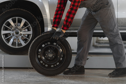 Mechanic holding a tire tire at the repair garage. replacement of winter and summer tires. © Serhii