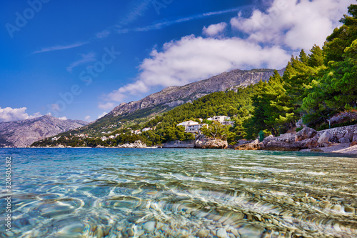 Fototapeta Naklejka Na Ścianę i Meble -  Amazing seascape of Adriatic sea.  Colorful summer view of small Brela beach Croatia, Europe. Croatian coast with clear water and pine trees around. Tropical viewpoint for design postcard.