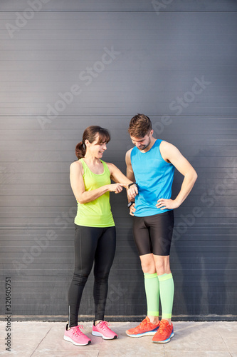 man and woman looking at watch after running.