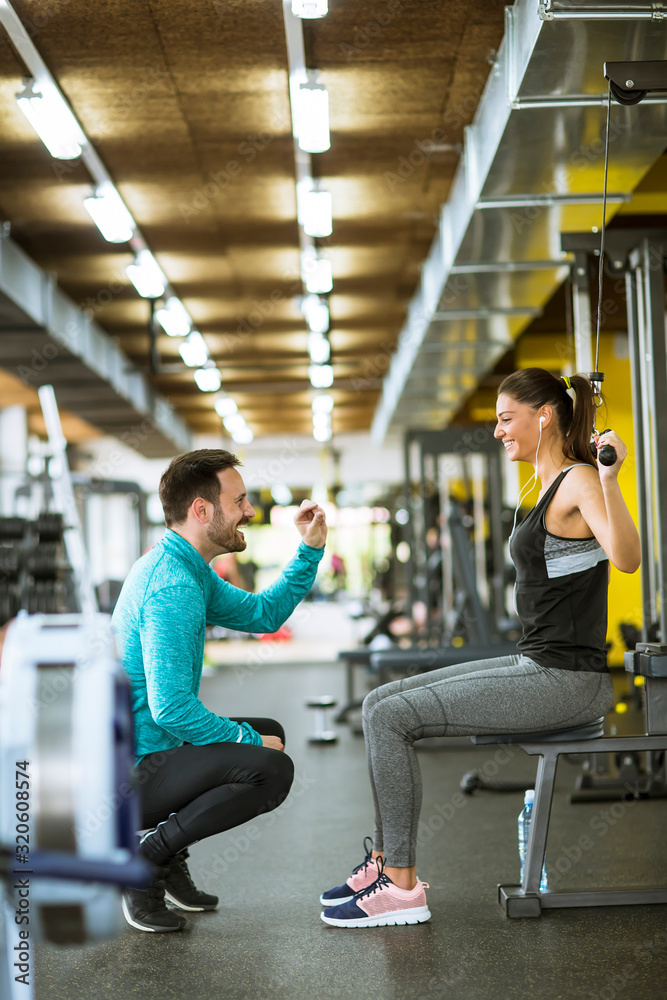Obraz premium Młoda piękna kobieta robi ćwiczenia z osobistym trenerem