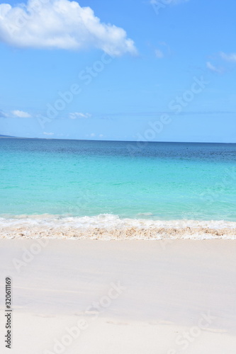 Sandy tropical beach and blue turquoise ocean water under blue sky © hhelene