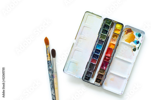 Set of watercolor paints and brushes often used by professional artist. Realistic image with spots, blots and traces of use. Isolated on white background