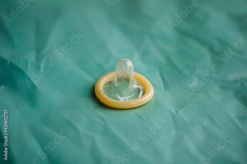 condom without packaging on a turquoise background