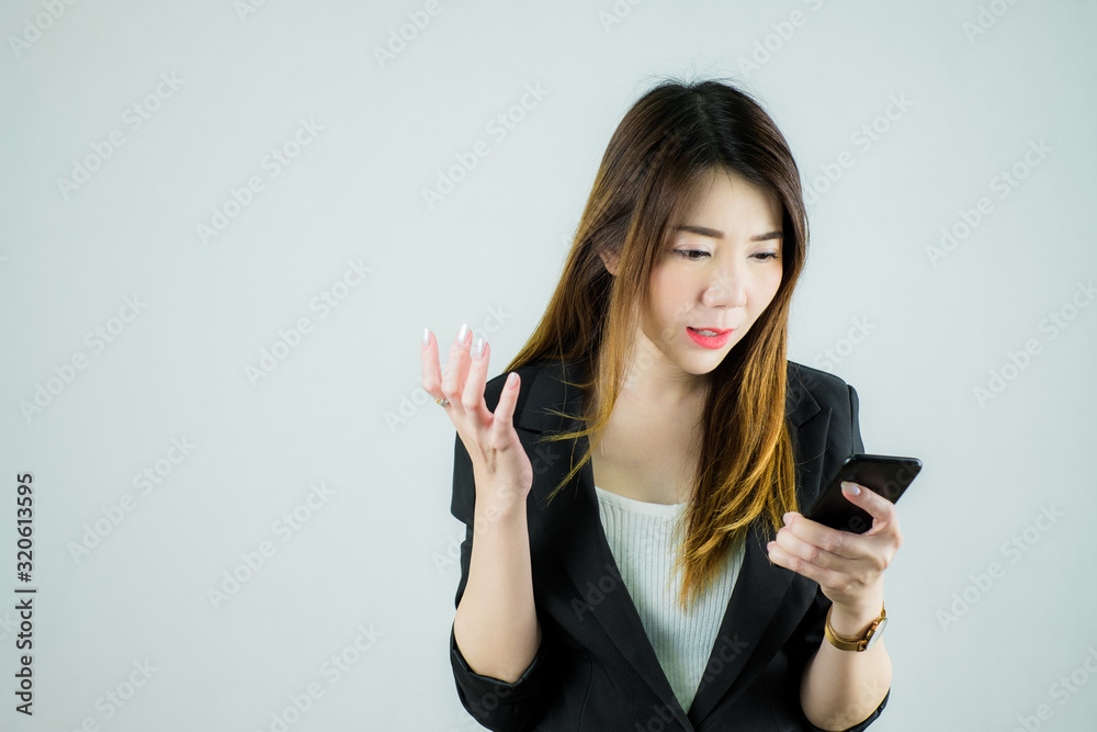 Portrait of angry asian business woman and looking at mobile phone. Caucasian female model isolated on white background. Portrait of angry asian business woman and looking at mobile phone. Caucasian female model isolated on white background.