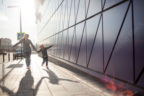 Fashion family dressed jeans wear and walking together in the street of the city. Poeple wearing denim clothes. Mother and daughter running at the background wall and sun