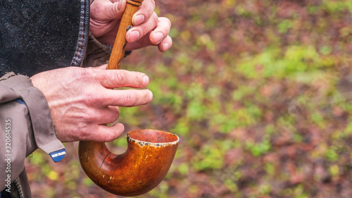 A close-up of the hands of a piper playing the bagpipe on the nature background.