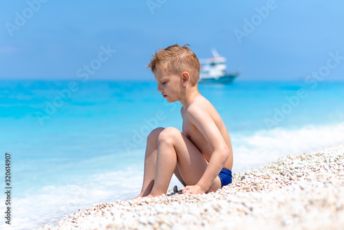 A boy is playing by the water on the beach