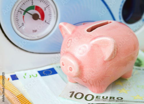 Natural gas saving, energy efficiency concept image. Pink piggy bank with Euro cash near a heating boiler at home in winter time.