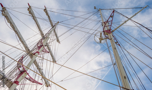 Rigging of a tall ship below a blue cloudy sky in sunlight in winter