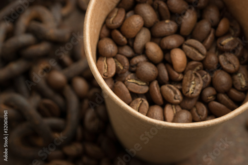Fototapeta Naklejka Na Ścianę i Meble -   Coffee beans in a paper cup close-up. The aroma of coffee, selected beans, arabica, energy, relaxation, pleasure.