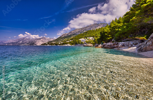 Fototapeta Naklejka Na Ścianę i Meble -  Amazing seascape of Adriatic sea.  Colorful summer view of small Brela beach Croatia, Europe. Croatian coast with clear water and pine trees around. Tropical viewpoint for design postcard.