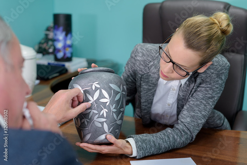 female funeral director showing urn to bereaved man photo