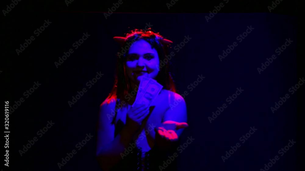 Woman devil with an ominous smile on her face seduces money to sell her soul Woman devil with an ominous smile on her face seduces money to sell her soul