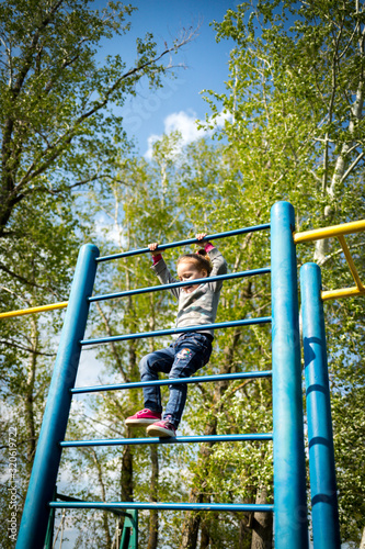 Fototapeta Naklejka Na Ścianę i Meble -  A small child climbs the swedish wall outdoors